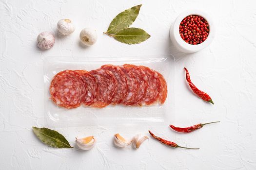 Salami slices vacuum plastic pack set, on white stone table background, top view flat lay
