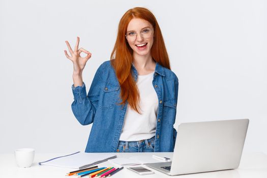 No problem, everything excellent. Confident creative redhead woman have plan, prepare design project, working with team on drawing, standing near table with laptop, colored pencils, show ok.