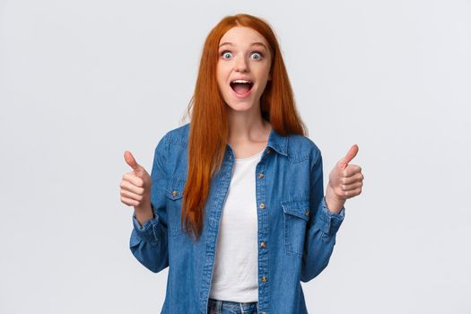 Speechless, excited and impressed redhead female cheering for friend scored goal, achieved success, great teamwork brought positive result, showing thumbs-up smiling and scream happy surprised.