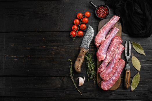 Duck necks raw, freshly set, on black wooden table background, top view flat lay, with copy space for text