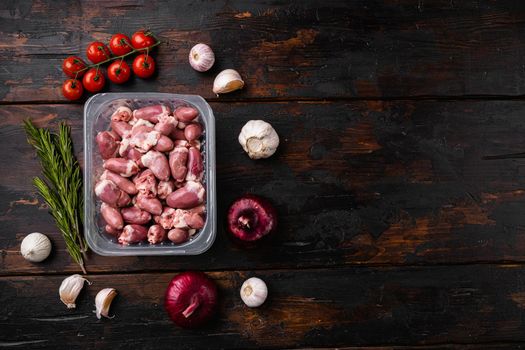 Raw fresh meat chicken hearts in plastic container set, on old dark wooden table background, top view flat lay, with copy space for text