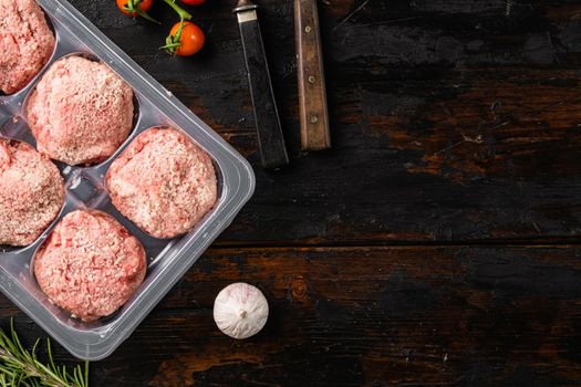 Semi finished products, meatballs, meat patties in plastic pack set, on old dark wooden table background, top view flat lay, with copy space for text