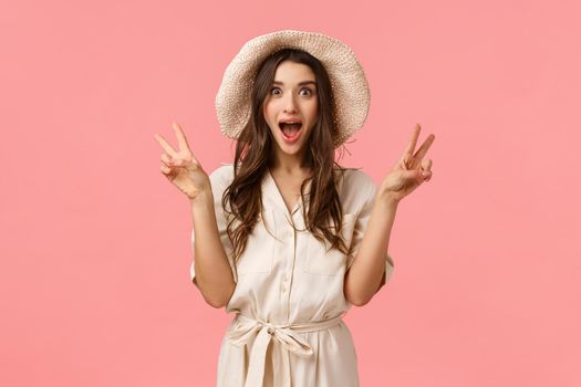 Amused, enthusiastic beautiful woman cheering as going shopping with girlfriends, girl getting married telling girlfriends great news and scream with overjoy, showing peace signs, smiling broadly.