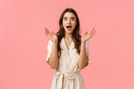 Pleased and surprised, happy young woman hearing great news, open mouth fascinated and amused, clap hands react surprise and amazing great event, standing pink background delighted.