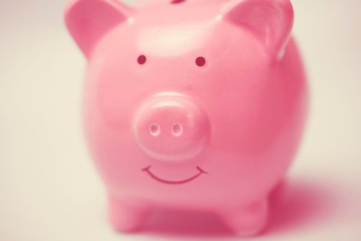 Piggy bank in the form of a smiling pink pig to save wealth, savings and financial success, close-up view.