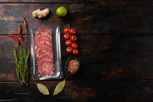 Salami slices vacuum plastic pack set, on old dark wooden table background, top view flat lay, with copy space for text