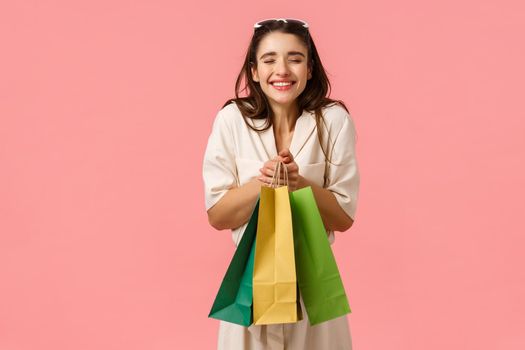 Excitement, consuming and shops concept. Cheerful and amused bride shopping for future wedding, screaming ecstatic, smiling happily holding bags enjoying buying things, standing pink background.