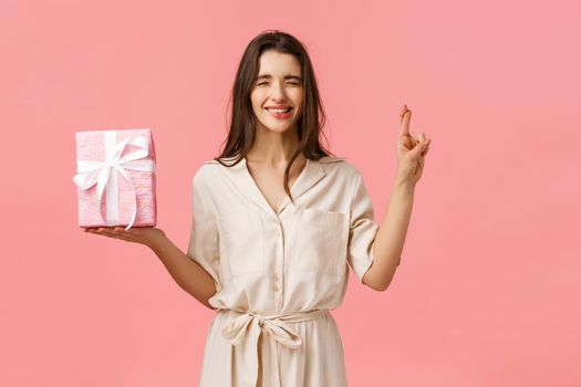 Anticipation, celebrating and presents concept. Cute b-day girl in lovely dress making wish, hope find exactly what she wished for inside gift box, cross fingers and close eyes, biting lip tempting.