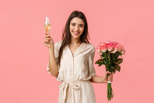 Celebration, cheer and beauty concept. Beautiful young tender female in dress, holding bouquet flowers, raising glass champagne, giving toast, smiling and enjoying party, pink background.