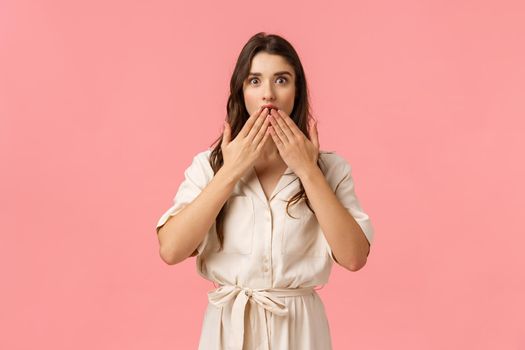 Surprised girl didnt expact friend kiss her, touching lip and looking amazed with wondered and excited expression, wearing cute dress, reacting astounded, standing pink background.