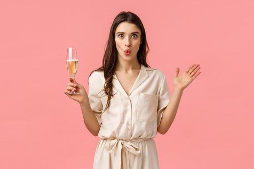 Wow wonderful news lets celebrate. Surprised and amused attractive brunette woman in dress, having fun partying, raising hands amazed, folding lips excited and holding glass champagne.