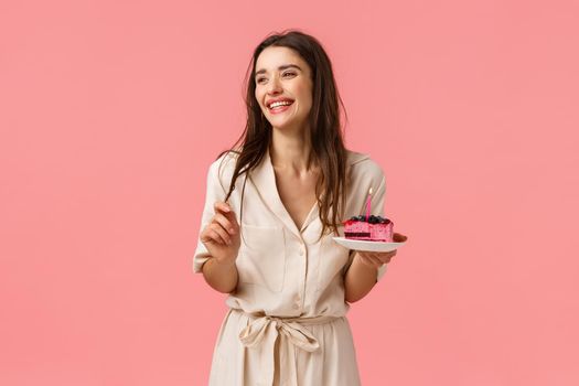 Celebration, happiness and holidays concept. Beautiful young woman having fun, holding plate with cake, smiling and laughing carefree, eating b-day dessert blowing-out candle, having fun.
