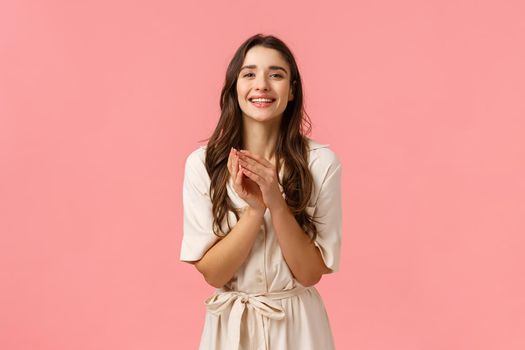 Tenderness, women and beauty concept. Cheerful charming young cute brunette girl with curly hair, get dressed date, press palms chest tender, smiling touched, being grateful, pink background.
