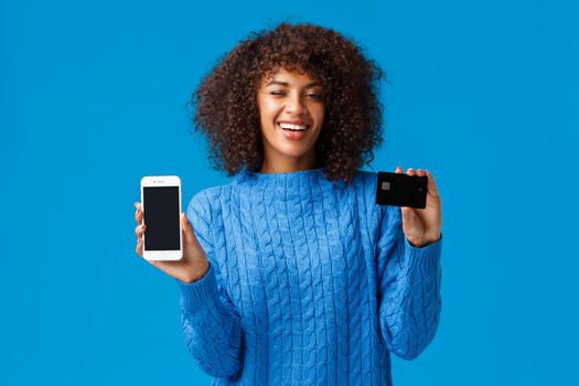 Dont waste your time standing queues, pay online. Relaxed and chill good-looking assertive smiling african american woman showing smartphone screen and credit card, wink cute.