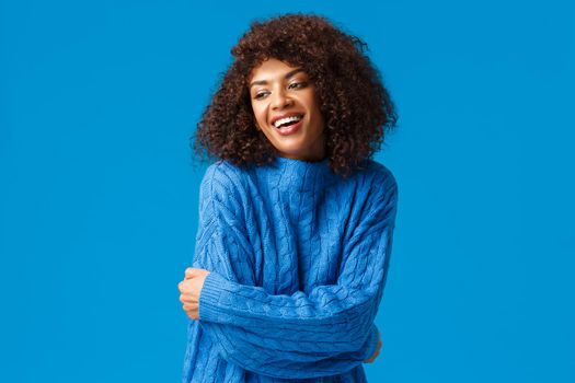 Tender, romantic and sensual smiling pretty african american girl, embracing own body, self-accaptence concept. cheerfully looking sideways, hugging herself to get warm these winter days.