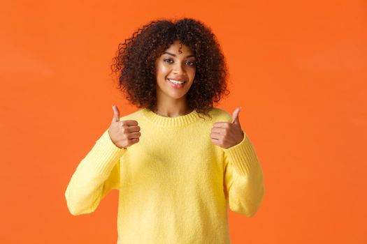 Waist-up shot cute supportive african-american woman feeling happy about great idea, shot thumb-up and smiling, agree with you, give positive answer, recommend product, orange background.