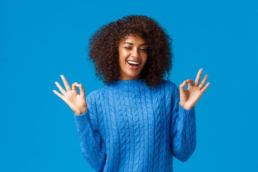 Relax and chill, everything good. Cheerful good-looking carefree young african-american woman showing calm down, okay gesture, assure all fine and smiling, standing blue background satisfied.