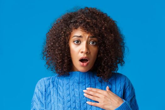 Concerned and worried shocked african-american woman pity for friend, heart bad news, touching heart and sighing with troubled upset expression, feeling uneasy for person, blue background.