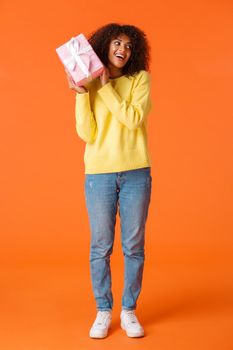 Full-length shot curious lovely african-american girl receive christmas present and interested whats inside, shaking gift box guess what there, smiling celebrating winter holidays, got present.