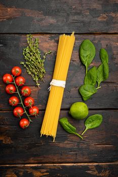 Bunch of spaghetti, raw pasta set, on old dark wooden table background, top view flat lay