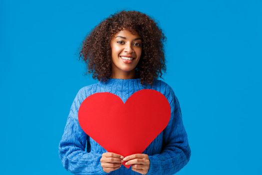 Be my valentine. Romantic and sensual cute african-american woman with afro haircut, holding big red heart sign and smiling, confessing love, searching soulmate, have perfect relationship.