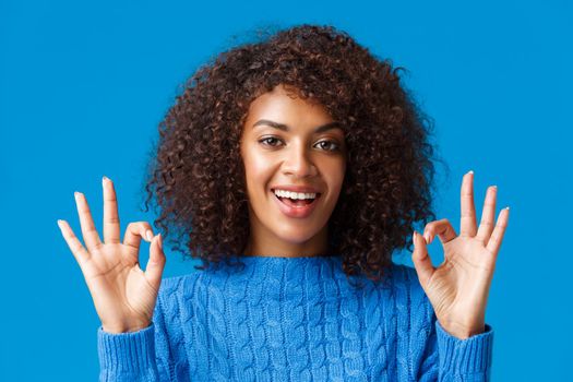 Close-up shot assured and assertive, confident young african american woman say everything under control, alright all good with okay gesture, smiling give approval, positive reply, blue background.