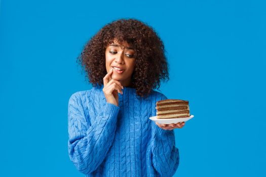 Girl want eat delicious piece cake but worry about diet and calories. Attractive silly african american woman trying resist temptation take bite of tasty dessert, looking with desire at plate.