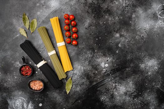 Italian noodles in three colors, black, yellow, green set, on black dark stone table background, top view flat lay, with copy space for text