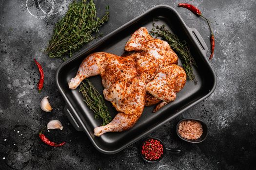 Marinated whole raw chicken tabaka set, on black dark stone table background, top view flat lay