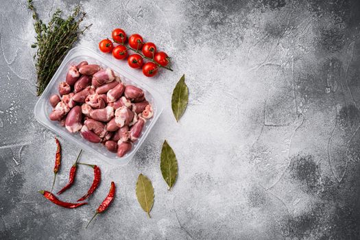 Raw fresh meat chicken hearts in plastic container set, on gray stone table background, top view flat lay, with copy space for text