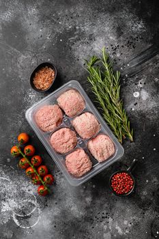 The patties of minced meat on a tray set, on black dark stone table background, top view flat lay