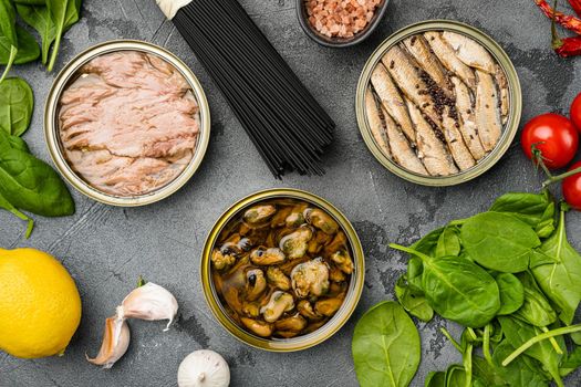 Opened cans with sardines, mussel, tuna set, on gray stone table background, top view flat lay