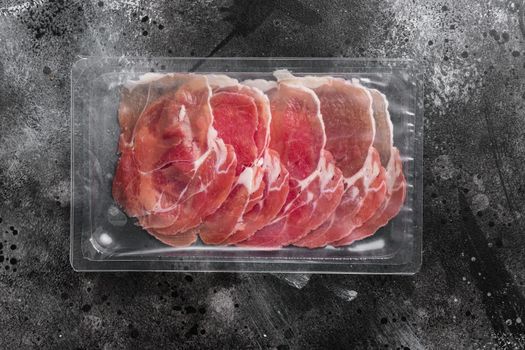 Prosciutto pack set, on black dark stone table background, top view flat lay, with copy space for text