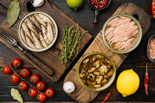 Cans of preserves with tuna, sprat and mussels set, on old dark wooden table background, top view flat lay