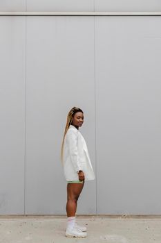 Young african american woman with braided hairstyle standing in street looking at camera. Copy space. Vertical image.