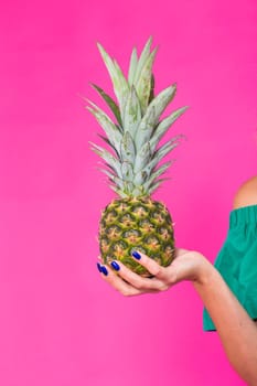 Closeup of woman and pineapple over pink background. Summer, diet and healthy lifestyle concept.