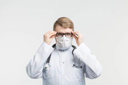 Health and medicine - doctor wearing the stethoscope and white mask on white background.