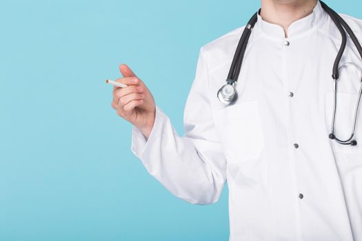 Stressed doctor smoking cigarettes on blue background.