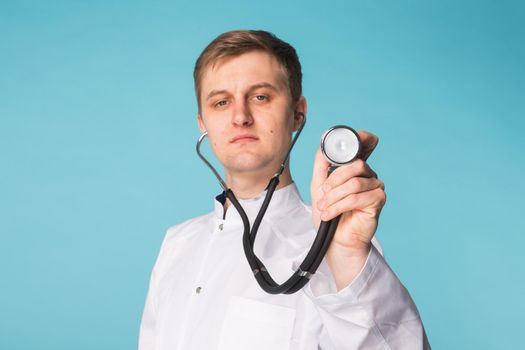 Doctor with stethoscope, close up over blue background.