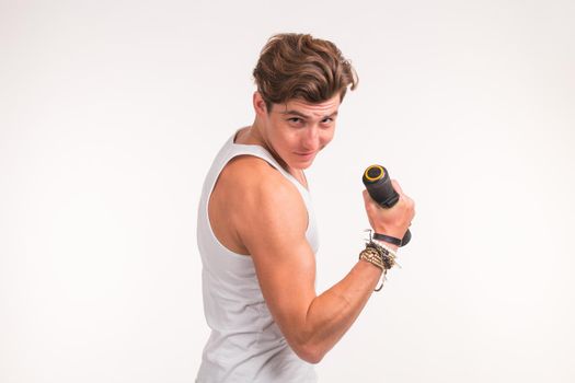 An attractive sporty man shows his biceps and smiling on white background.