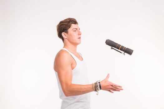 Expression, fitness and people concept - Handsome man throwing up a dumbbell over white background.