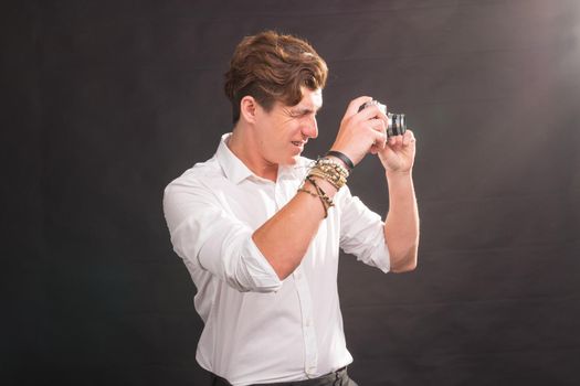 Technology, photography and hobby concept - man with retro camera, taking a photo of you over the grey background.