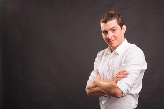 Confident handsome man with crossed arms over gray background with copy space.