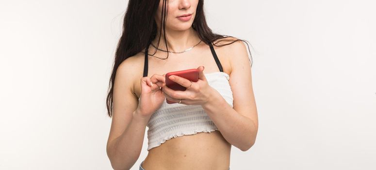 Close up of woman with long dark hair holding smartphone on white background with copy space.
