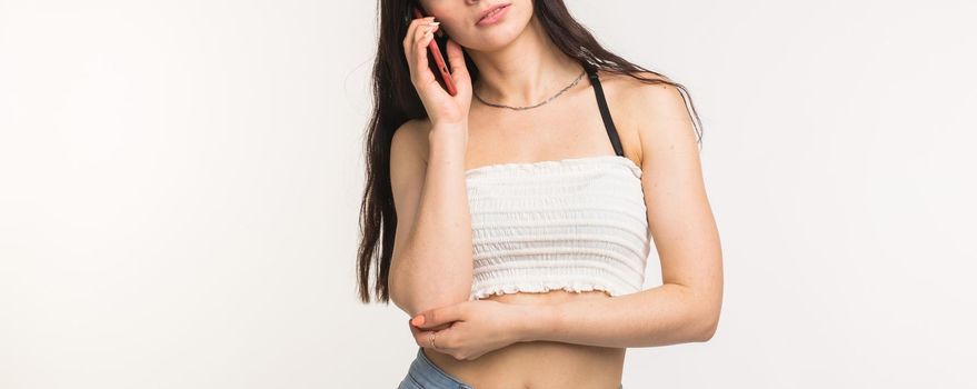 Technology and people concept - Cheerful young woman talking on cellphone on white background.