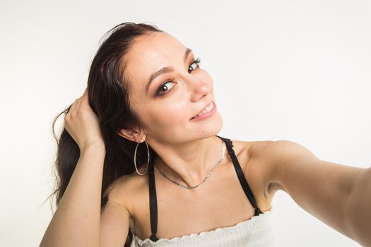 Close-up of young beautiful woman taking selfie on white background.