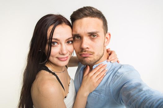 Young attractive couple taking selfie together on white background.