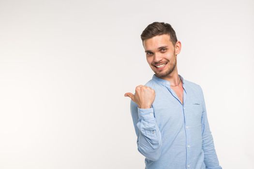 Advertisement and gesture concept - Successful man with smile on white background is pointing on empty copy space with his fingers.