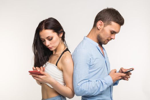 Smartphone addiction concept - Upset couple standing back to each other on white background.