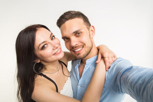 Relationship and people concept- man taking selfie with his wonderful woman on mobile phone over white background.